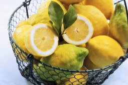 Bio-Zitronen in einem Drahtkorb, eine davon halbiert