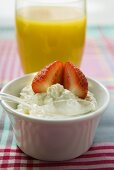 Cottage cheese with strawberry in front of orange juice