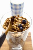 Crunchy muesli with blueberries and wooden spoon in a glass