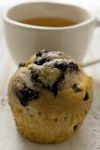 Blueberry muffin in front of a cup of tea