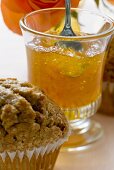 Orangengelee in einem Glas, davor ein Muffin