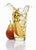 Wedge of pear falling into a glass of pear juice