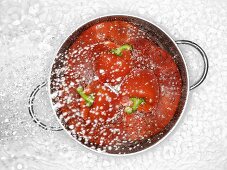 Peppers in a colander being sprayed with water