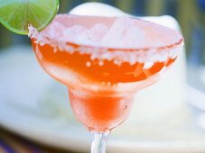 Limetten-Cocktail in orangefarbenem Glas