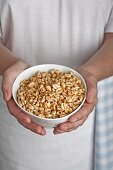 Hands holding a bowl of puffed wheat breakfast cereal