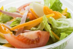 Mixed salad with ham and egg in plastic container