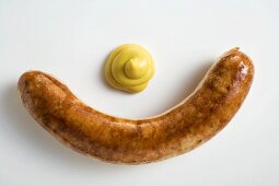 Eine Bratwurst mit Senf auf weißem Untergrund