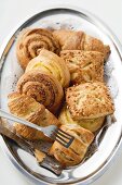 Assorted Danish pastries on silver platter with cake tongs