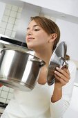 Woman holding steaming pan with lifted lid