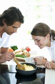 Young couple cooking scrambled eggs