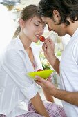 Man feeding woman a fresh strawberry