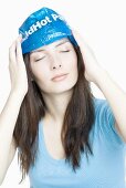 Young woman cooling her forehead with an ice pack