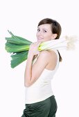 Young woman carrying fresh leeks on her shoulder