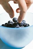 Hand reaching for blueberries in a small bowl