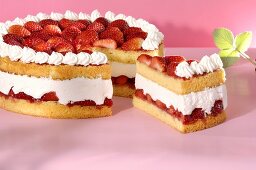 A strawberry cream cake with a piece cut