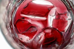 A glass of red fruit juice with ice cubes