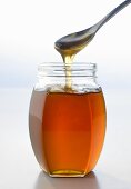 Honey running from spoon into jar