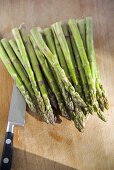 Green asparagus and knife on a wooden board