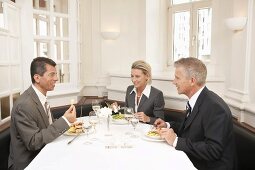 A woman and two men at a business meal