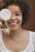 Young woman holding a cosmetic pad in front of her face