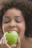 Junge Frau beisst in einen Apfel