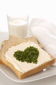 Soft cheese on toast with chives in heart shape, glass of milk