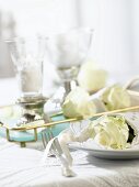 Two windlights and place-setting with white rose