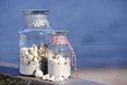 Zwei Vorratsgläser mit Sand und Muscheln gefüllt