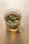 A glass cup of sage tea with sage leaves