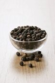 Black peppercorns in a small glass dish