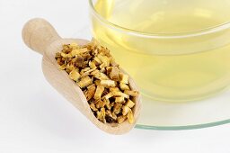 Dried angelica root in wooden scoop and cup of tea