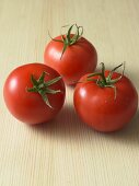 Three fresh tomatoes on wooden background