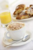 Eine Tasse Cappuccino, Orangensaft und Brioches