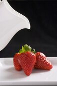 Three fresh strawberries with a cream jug