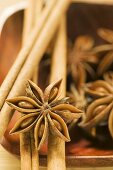 Star anise and cinnamon sticks in wooden bowl