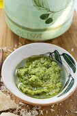 Pesto with olive oil in small bowl, Parmesan