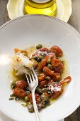 Roasted tomatoes with capers, white bread on fork, olive oil