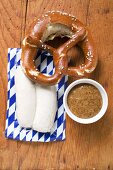 Two Weisswurst in packaging, pretzel & mustard