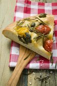 Slice of pizza with cherry tomatoes, capers and rosemary