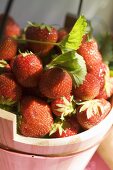 Fresh strawberries with leaves in wooden bucket