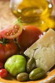 Tomaten, grüne Oliven und Parmesan auf Teller, Olivenöl