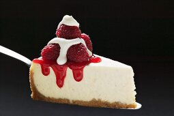 Slice of cheesecake with raspberries & cream on cake server