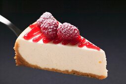 Slice of cheesecake with sugared raspberries on cake server