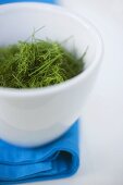 Chopped dill in white bowl on blue cloth