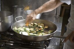 Turning courgette slices in frying pan