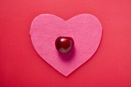 A cherry on a pink fabric heart