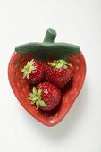 Three strawberries in red strawberry-shaped dish
