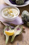 Fresh artichokes, lemons and bowl of lemon water