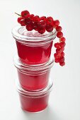 Three jars of redcurrant jelly with fresh redcurrants