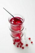 Three jars of redcurrant jelly, one opened, with spoon